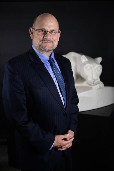 Kevin Snider, chancellor, stands in front of lion shrine statue