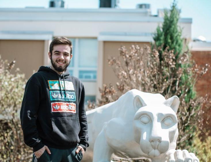 Student stands next to lion statue